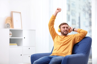 Photo of Young man with headphones resting in armchair at home