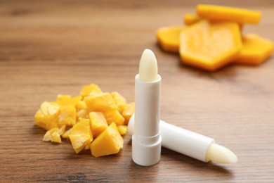 Photo of Hygienic lipsticks and natural beeswax on wooden table