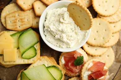 Photo of Different snacks with salted crackers on board, closeup