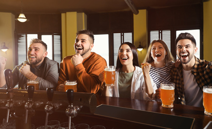 Photo of Group of friends watching football in sport bar