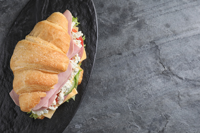 Photo of Tasty croissant sandwich with ham on grey table, top view. Space for text