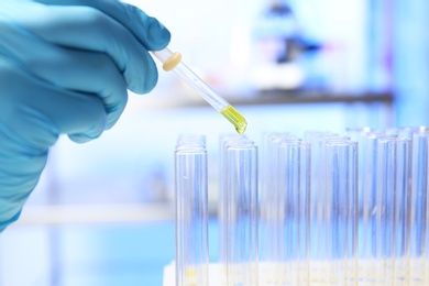 Photo of Laboratory assistant dripping urine sample for analysis from pipette into test tube, closeup