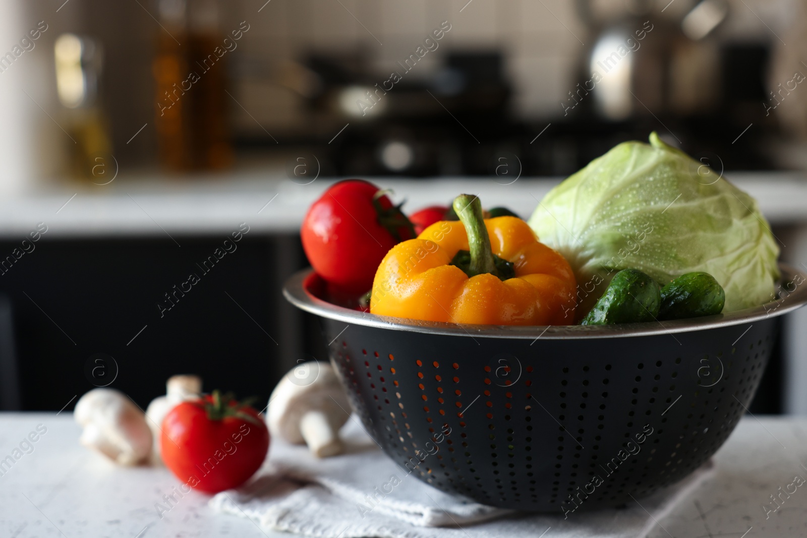 Photo of Metal colander with different wet vegetables on white textured table