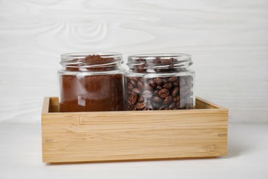 Photo of Jars with ground coffee and beans on white wooden table
