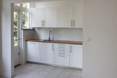 Photo of Interior of modern kitchen with stylish white furniture