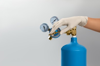 Photo of Medical worker checking oxygen tank on light grey background, closeup. Space for text