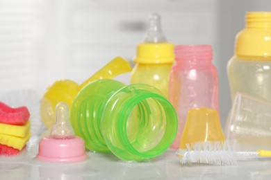 Photo of Clean baby bottles and nipples after sterilization near brush on white table, closeup