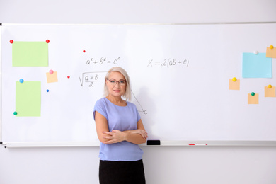 Mature teacher near whiteboard in modern classroom