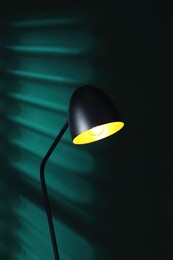 Photo of Stylish black lamp near green wall indoors
