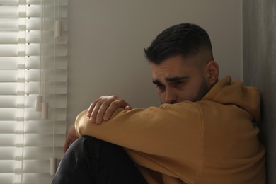 Photo of Sad man sitting near window at home