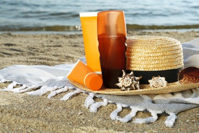 Photo of Sun protection products and beach accessories on blanket near sea, space for text