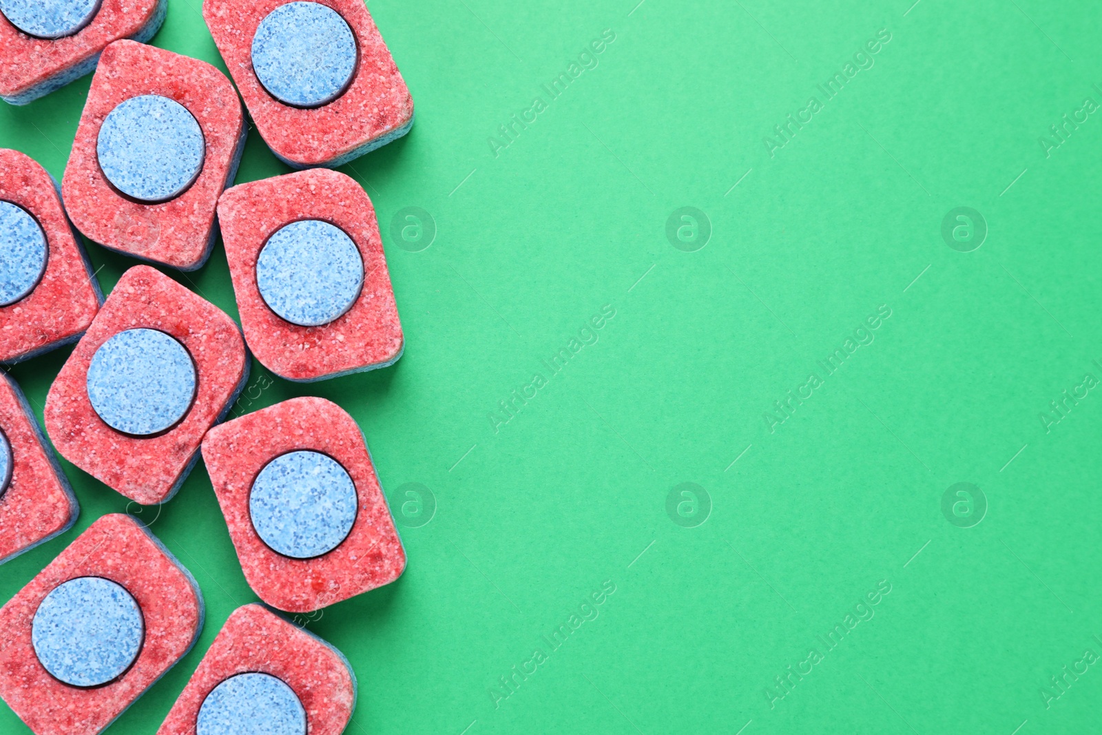 Photo of Many dishwasher detergent tablets on green background, flat lay. Space for text