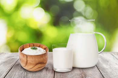 Image of Set of different dairy products on wooden table outdoors