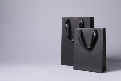 Photo of Black paper bags on light grey background, space for text