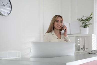 Photo of Receptionist talking on phone at countertop in office, space for text