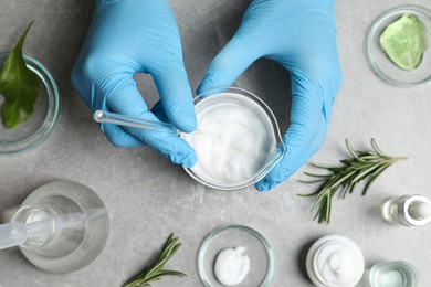Photo of Scientist making cosmetic product at grey table, top view