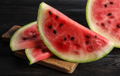 Photo of Wooden board with juicy watermelon slices on table