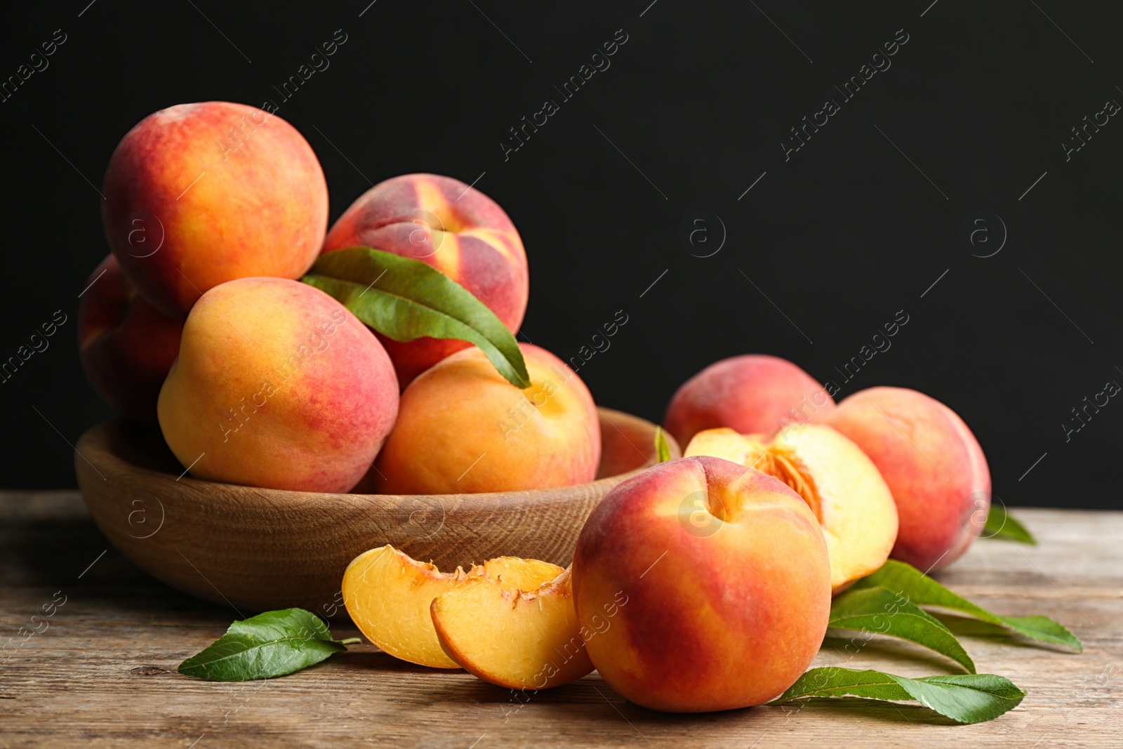 Photo of Fresh sweet peaches on wooden table against black background