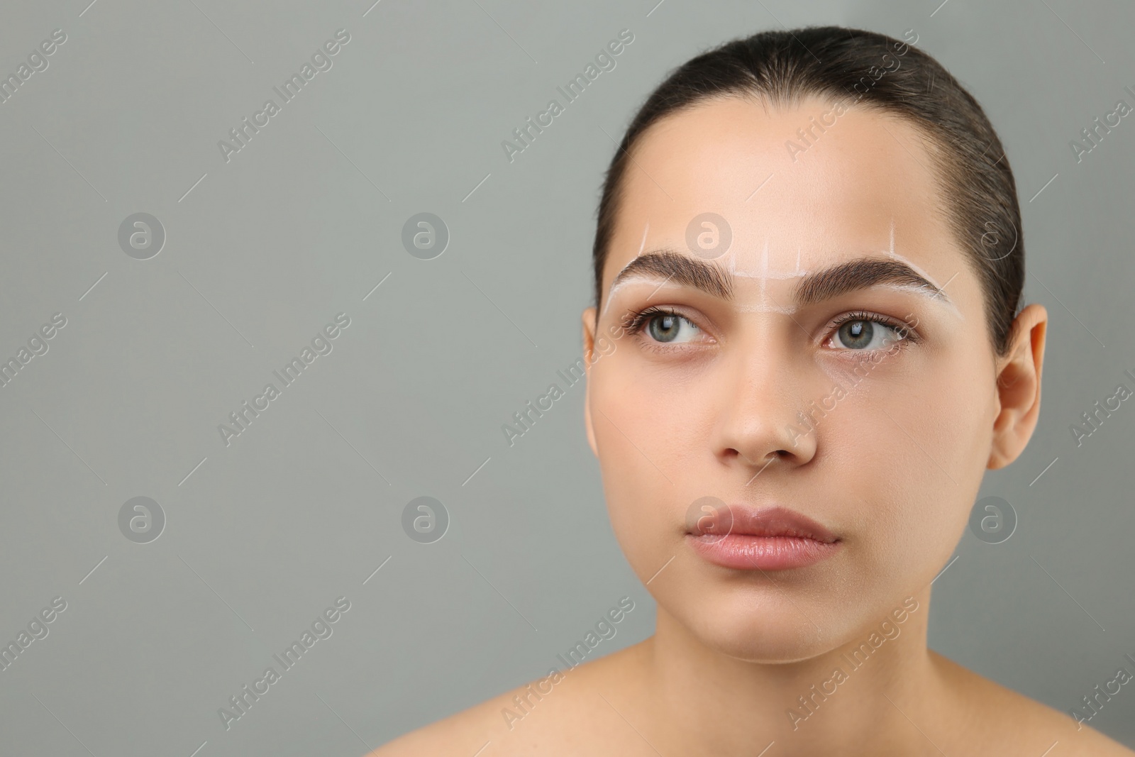 Photo of Eyebrow correction. Young woman with markings on face against grey background, space for text