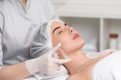 Photo of Professional cosmetologist holding skincare ampoule while working with client in clinic, closeup