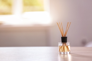 Photo of Aromatic reed air freshener on table against blurred background