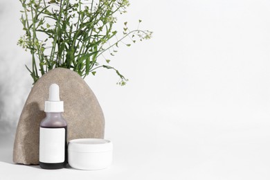 Photo of Cosmetic products, stone and bunch of camelina sativa on white background. Space for text