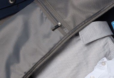 Photo of Man packing suitcase on wooden floor, top view with space for text. Business trip planning