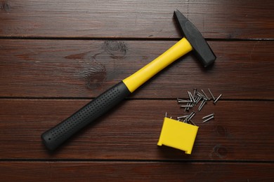 Photo of New hammer and metal nails on wooden table, flat lay. Professional construction tool