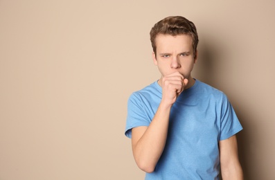 Photo of Teenage boy suffering from cough on color background. Space for text
