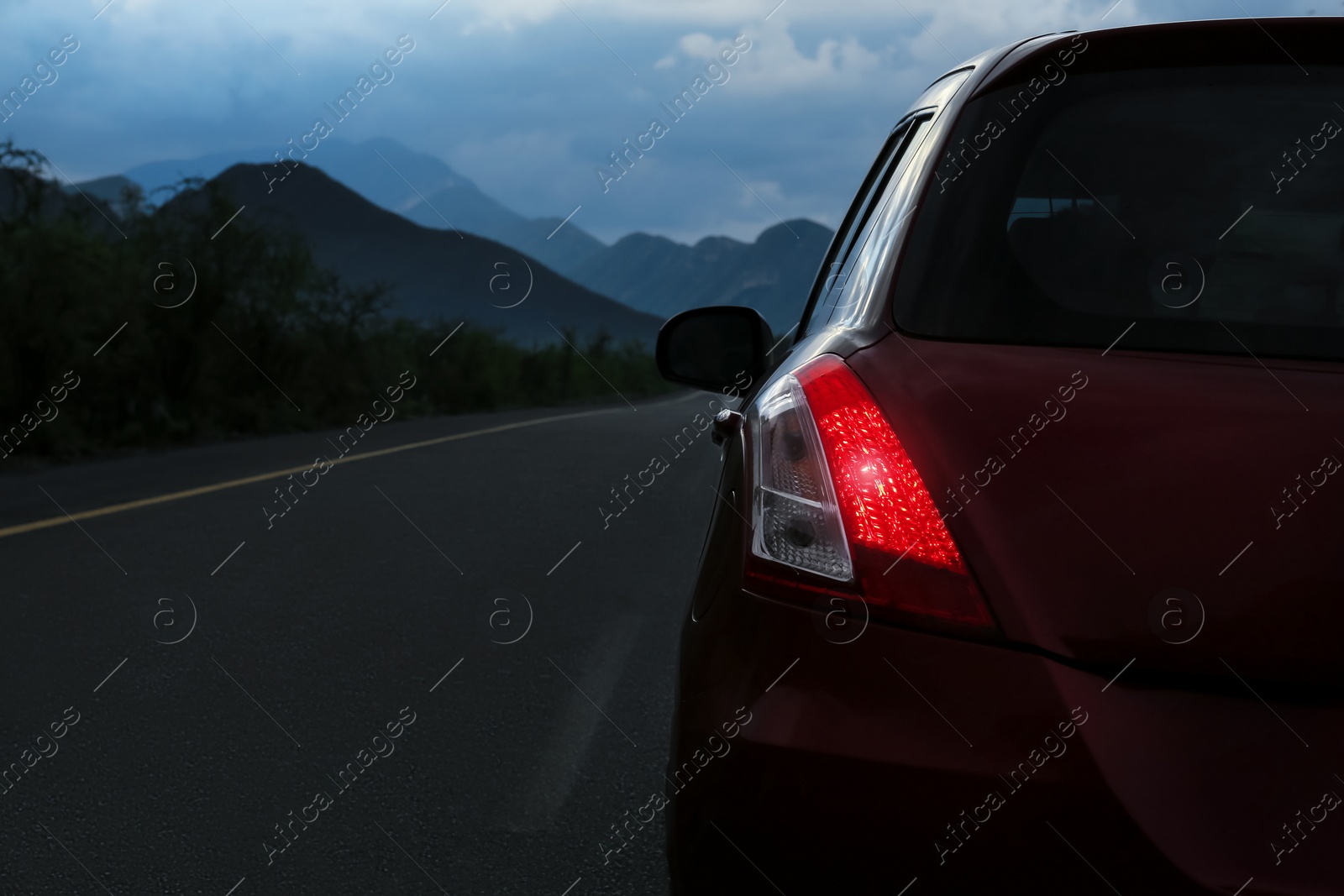 Photo of Beautiful view of mountains and car on asphalt highway outdoors, closeup. Road trip