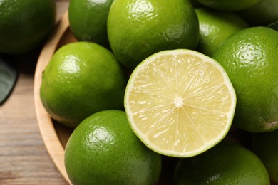 Photo of Whole and cut fresh limes on table, closeup