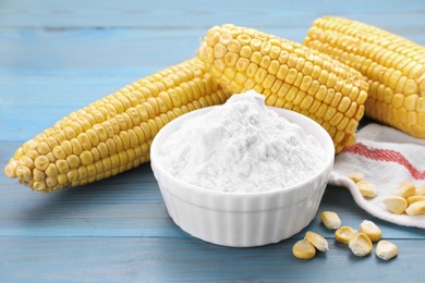 Photo of Bowl with corn starch, ripe cobs and kernels on light blue wooden table