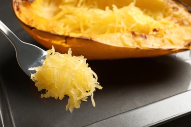 Photo of Fork with flesh of cooked spaghetti squash on blurred background, closeup