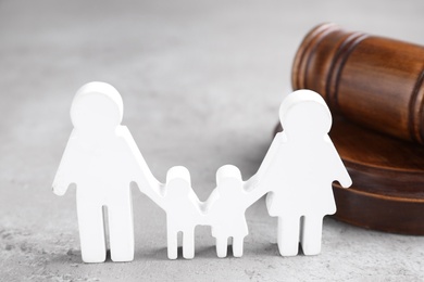 Photo of Figure in shape of people and wooden gavel on grey table. Family law concept