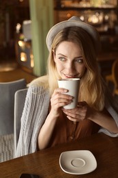 Photo of Young woman drinking coffee at cafe in morning