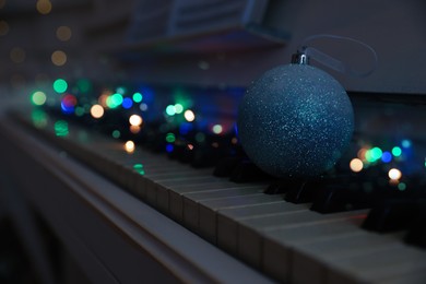 Photo of Beautiful bauble and fairy lights on piano keys, space for text. Christmas music