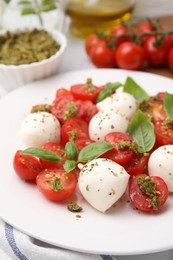 Photo of Tasty salad Caprese with tomatoes, mozzarella balls and basil served on table, closeup