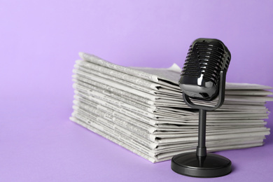 Photo of Newspapers and vintage microphone on light violet background. Journalist's work
