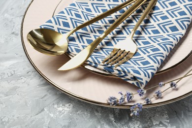 Photo of Clean plates, cutlery, napkin and lavender flowers on light grey textured table, closeup