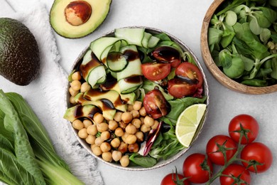 Photo of Delicious salad with balsamic vinegar and ingredients on white table, flat lay