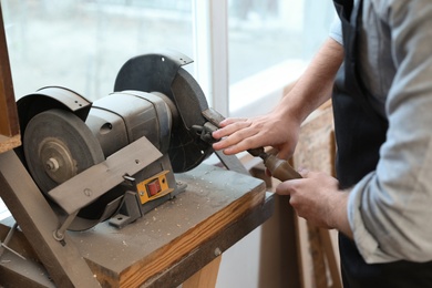 Photo of Working man using grinding machine at carpentry shop, closeup
