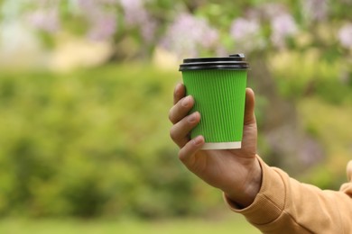 Photo of Man with takeaway coffee cup in park, closeup. Space for text