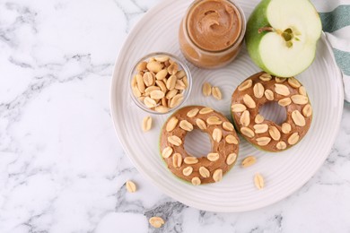 Photo of Fresh green apple with peanut butter and nuts on white marble table, top view. Space for text