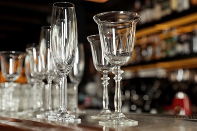 Photo of Different empty clean glasses on counter in bar