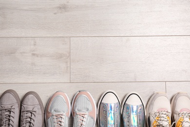 Photo of Different sneakers on wooden floor, top view with space for text