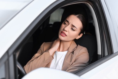 Photo of Young woman suffering from neck pain in her car