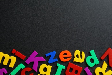 Photo of Plastic magnetic letters on black background, top view with space for text