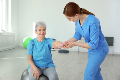 Photo of Professional physiotherapist working with elderly patient in rehabilitation center