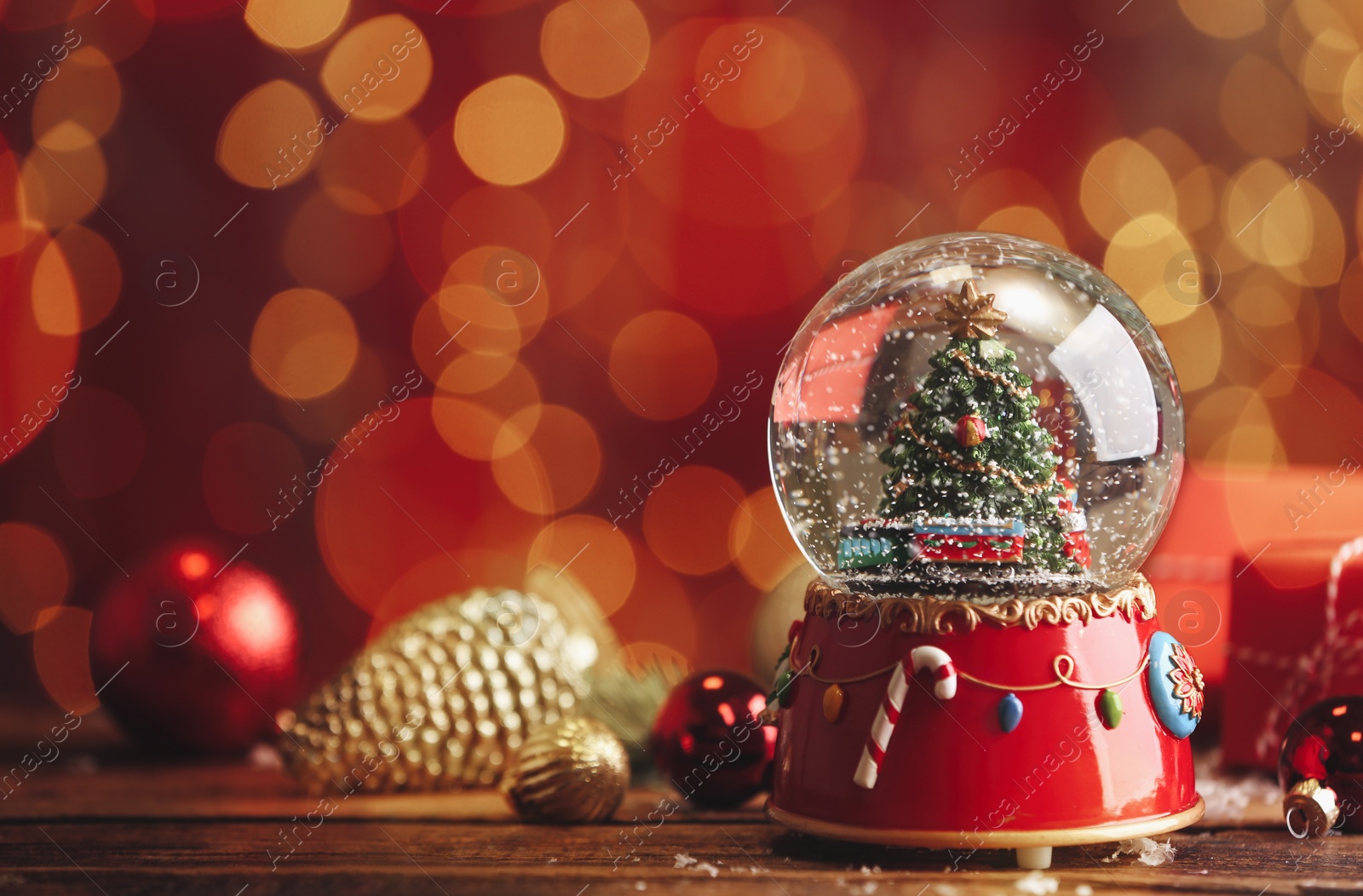 Photo of Beautiful snow globe with Christmas tree on wooden table against blurred festive lights. Space for text