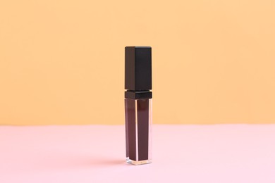 Photo of One purple lip gloss on color background